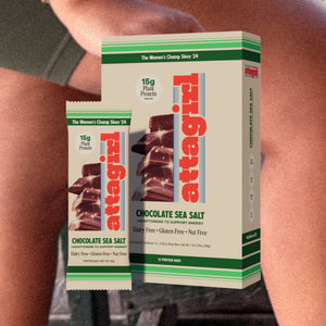 Athletic woman on track field with Attagirl chocolate sea salt protein bar – clean fuel with 15g plant protein