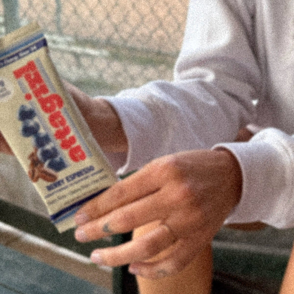 Female athlete sitting on bench holding Attagirl berry espresso protein bar – plant-based, high protein